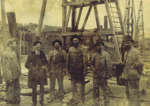 Jim Burke on refinery site with his felloe workers. He is the one on the right wearing the derby – the hard hat of his day.