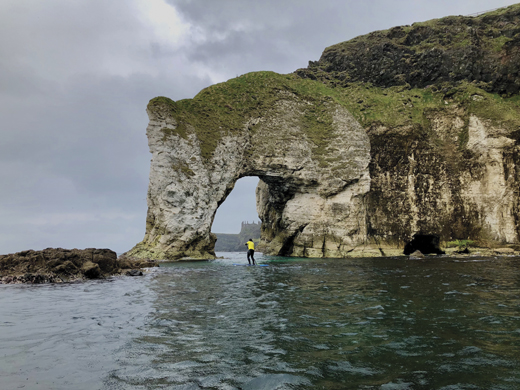 Ricky Martin of Alive Surf School paddles towards the trunk of Elephant Rock with Dunluce Castle in the background.