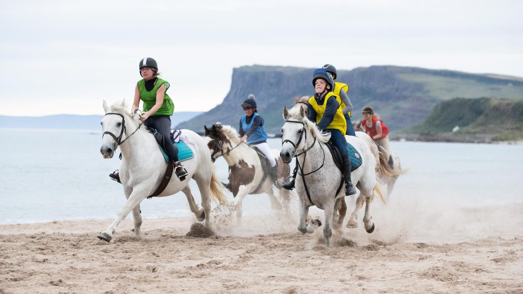 Horse racing on the beach with Fairhead in the background during the Ould Lammas Fair.