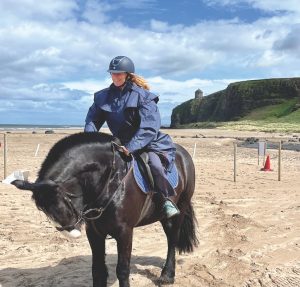 Kendra, an Irish Cob horse, takes a bow after taking Pam Martin along Benone Beach to Mussenden Temple, shown on a cliff in the background.