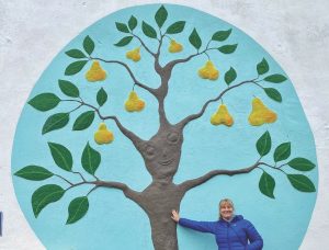 Pam Martin poses with the Pear Tree which has a happy face mural that greets visitors to the twin's shop and cafe.